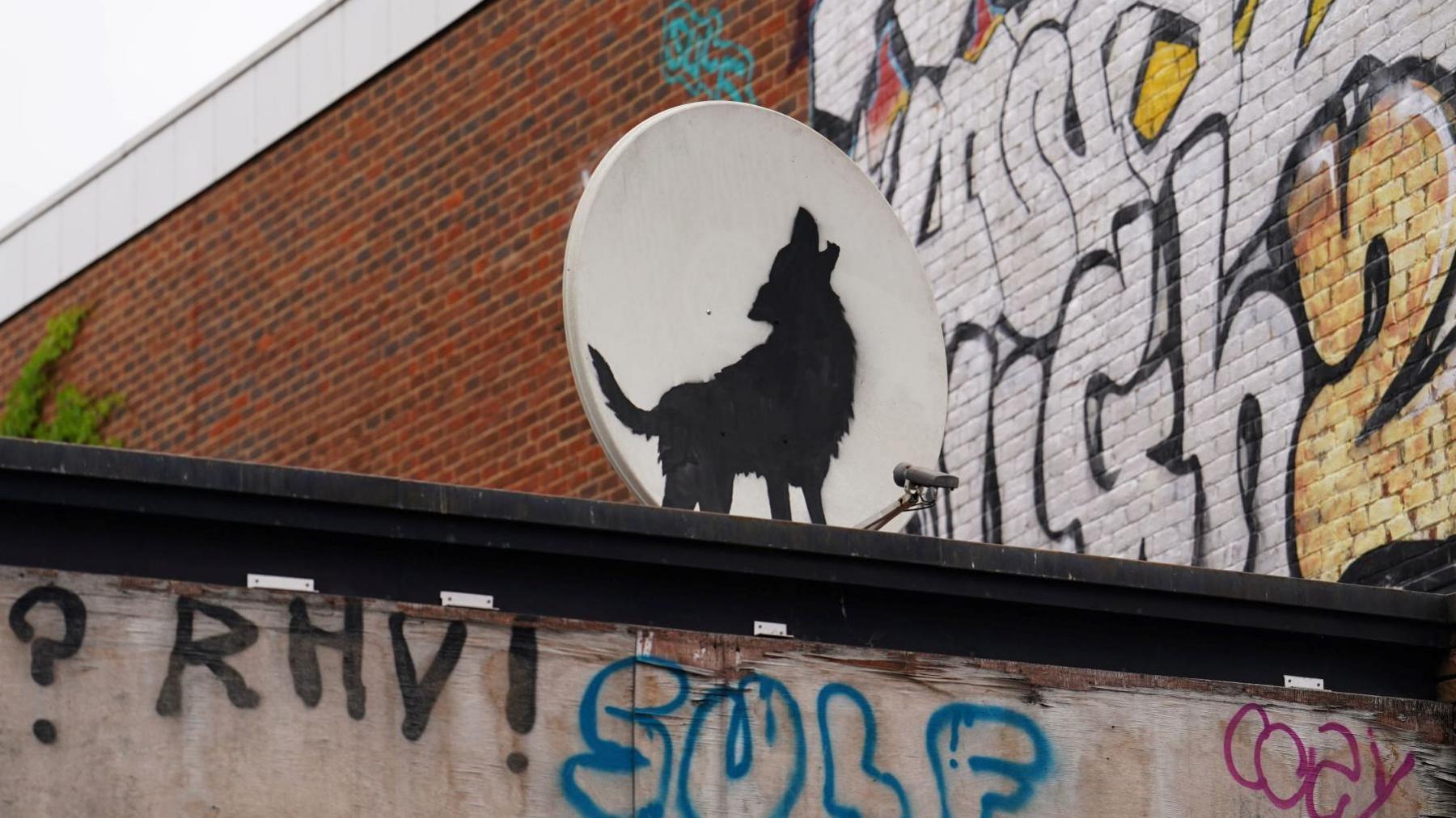 Banksy's image of a howling wolf appearing as though in front of the moon