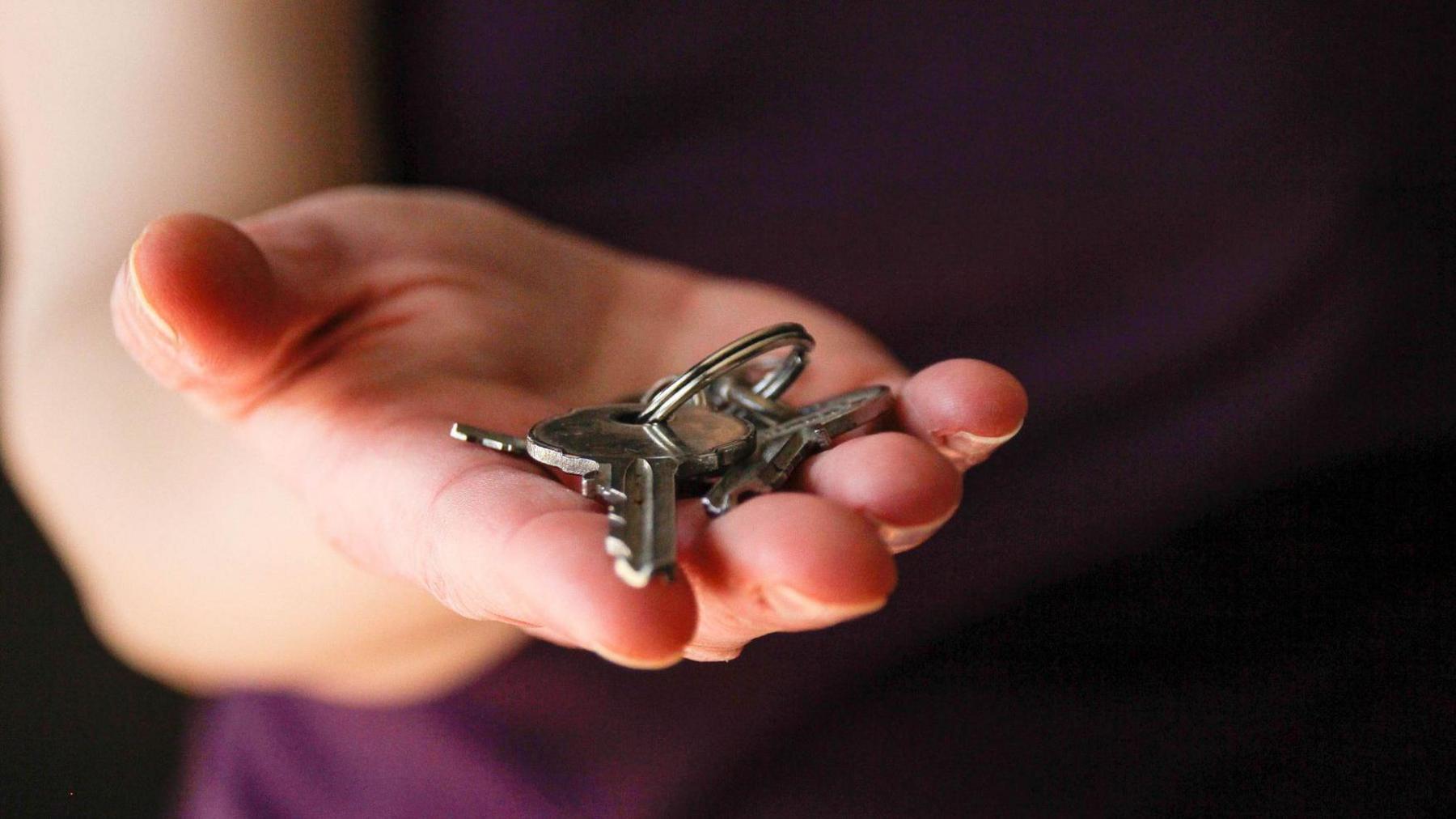 A stock image of someone holding a set of house keys.