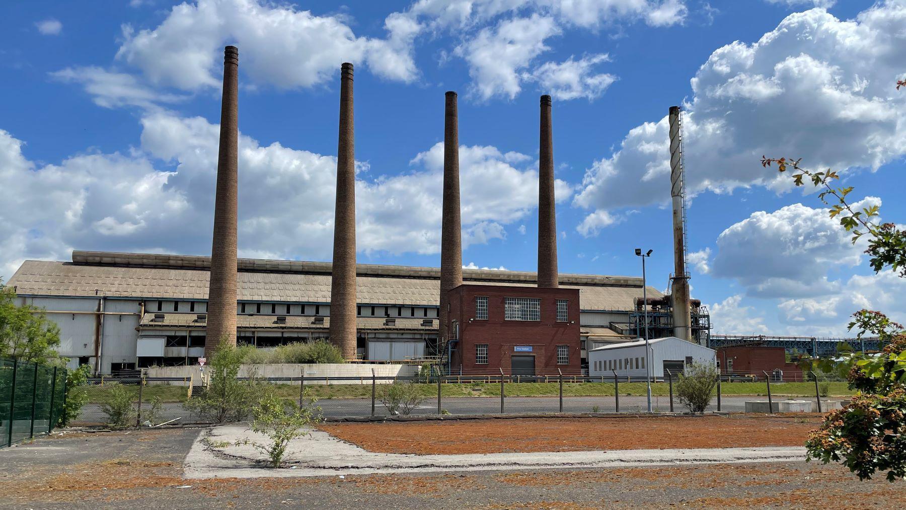 A factory with five large chimneys on a sunny day.