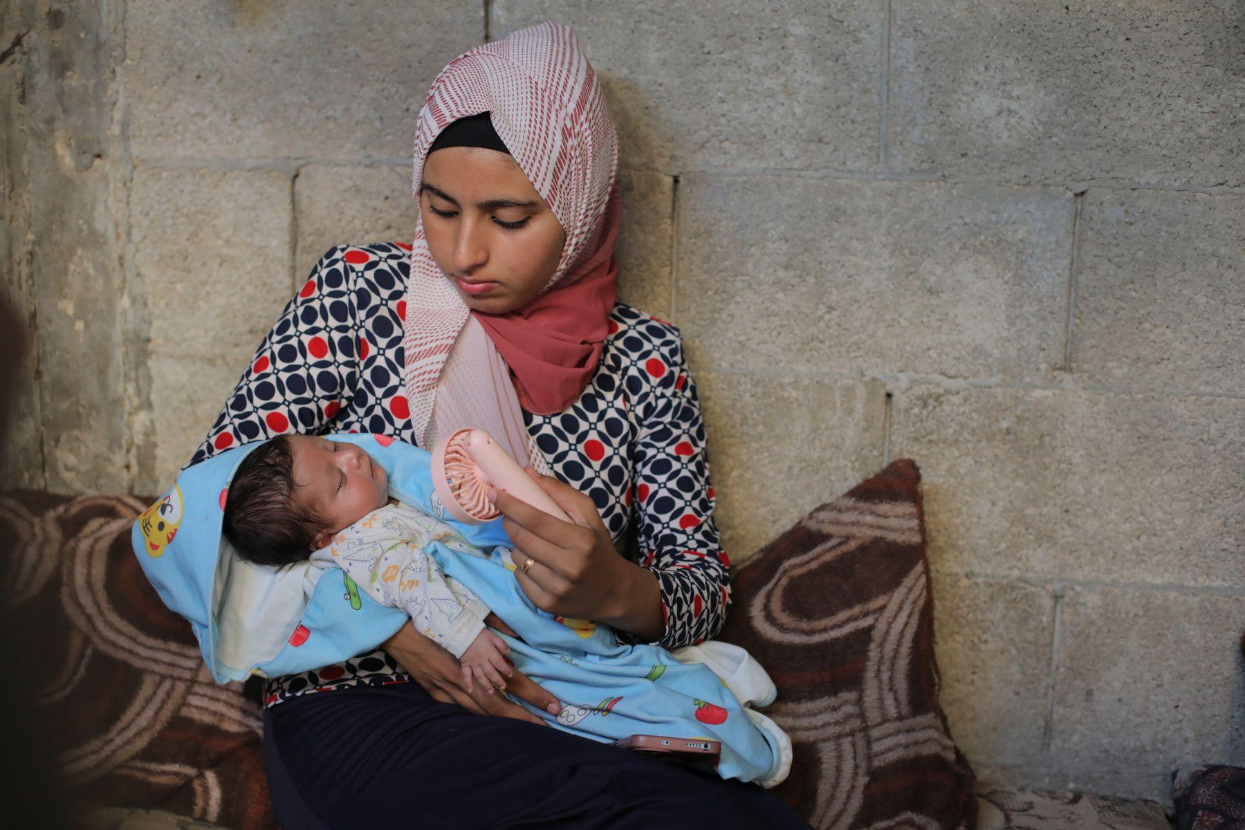 A Palestinian woman cools off her child while sleeping inside the tent at a refugee camp in Deir al-Balah, Gaza, on June 11, 2024.