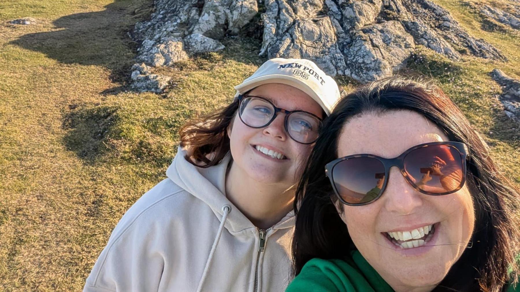 Daisy yn sefyll ochr yn ochr â’i mam, y ddwy yn edrych tuag at y camera, yn ystod cyfnod ei thriniaeth