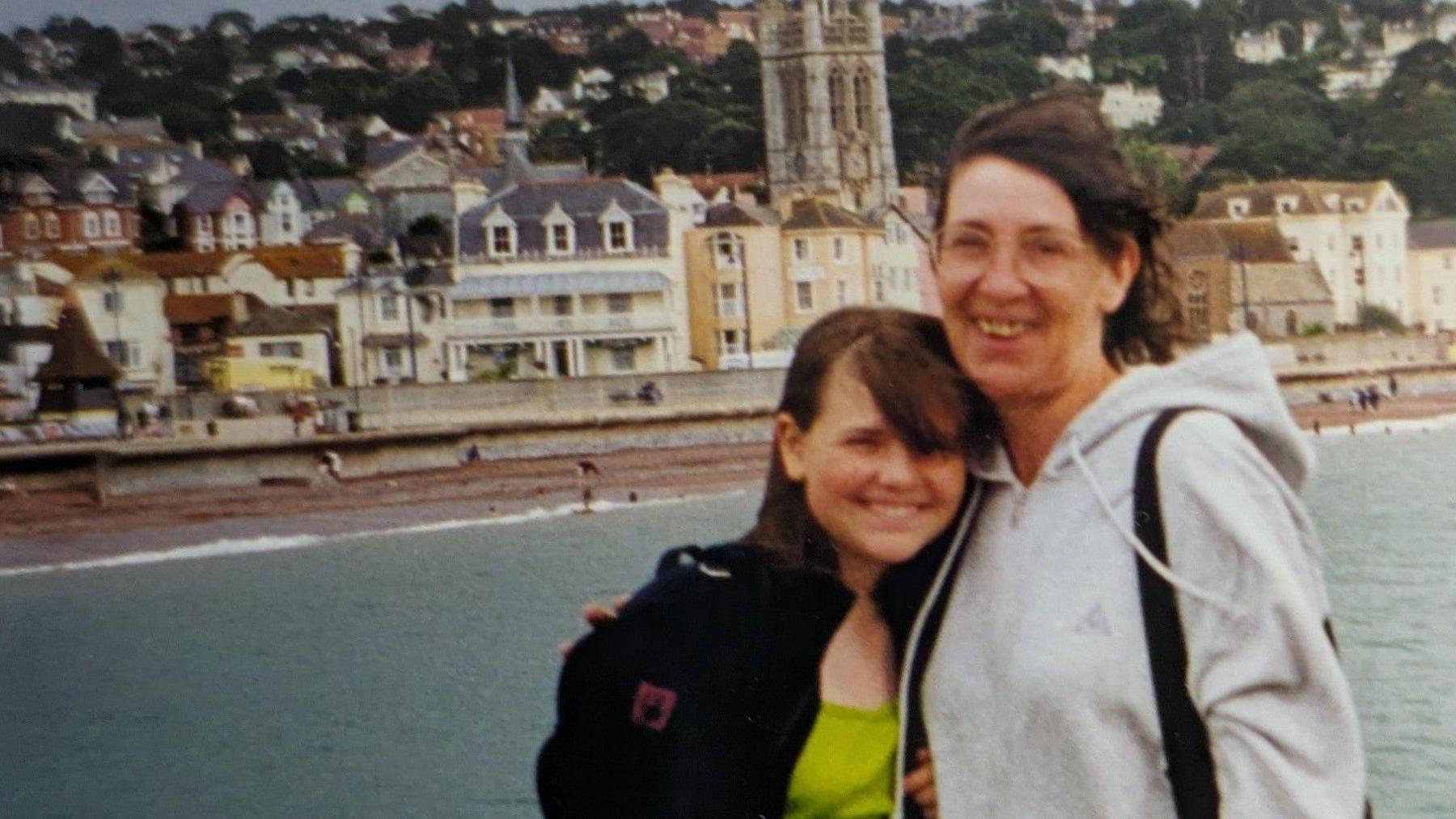 An old photograph, potentially from the nineties, of a teenage girl and her mum smiling at the seaside