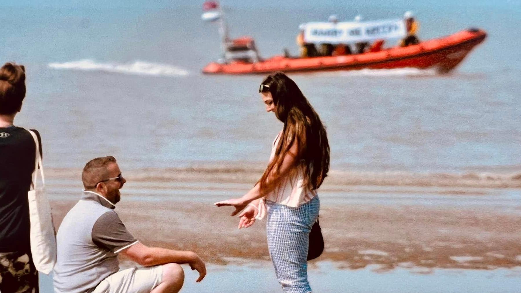 Man on one knee proposing by sea