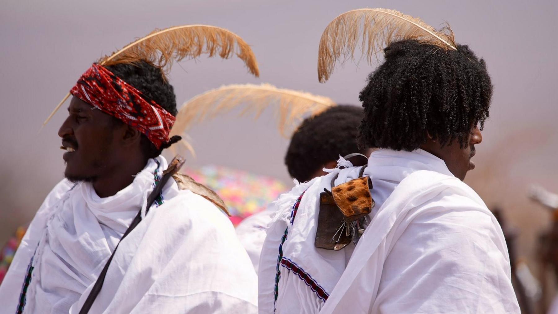 Young men wear feathers in their hair to show their status as initiates.