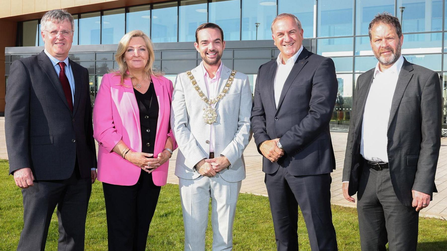 Four men and a woman standing on grass outside the new Black Mountain Shared Space building. 