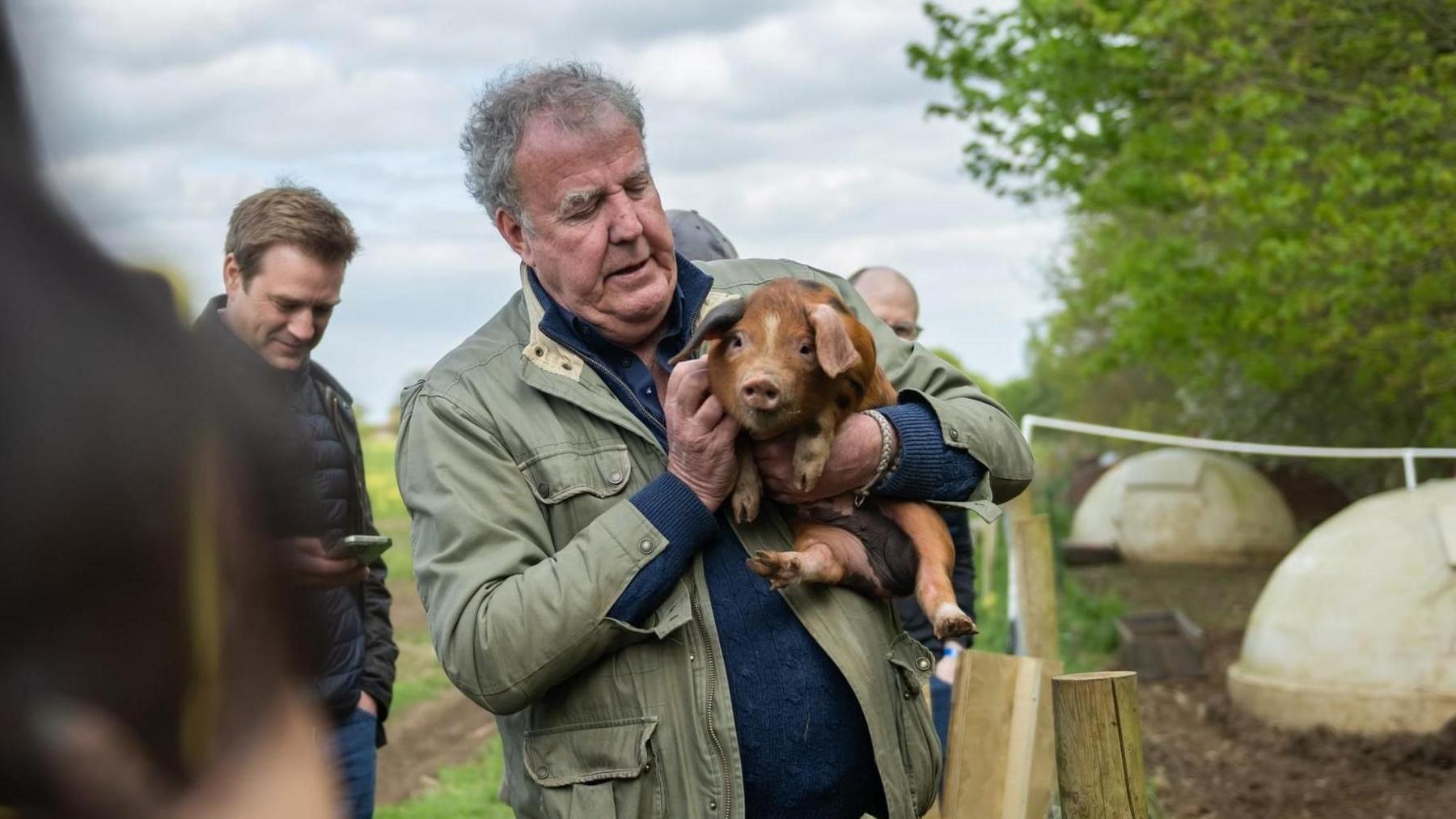 Jeremy Clarkson holding a piglet on a farm