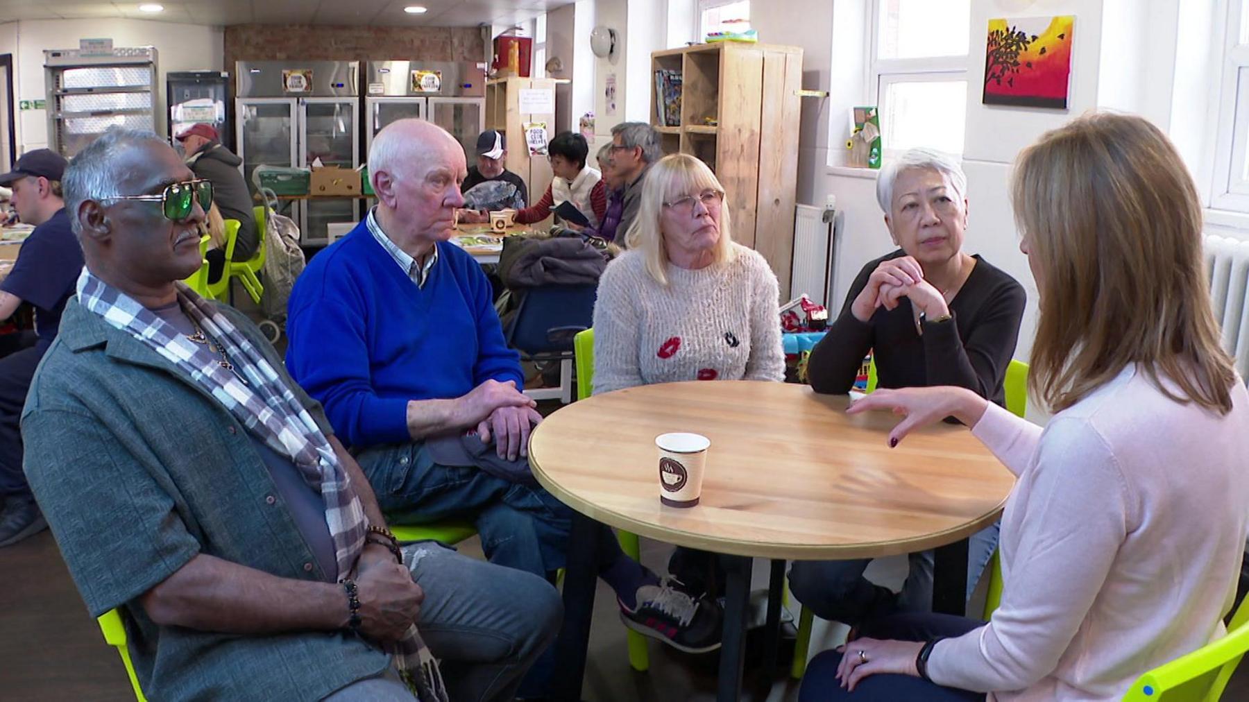 Two male and two female pensioners sat at table in community centre in Salford