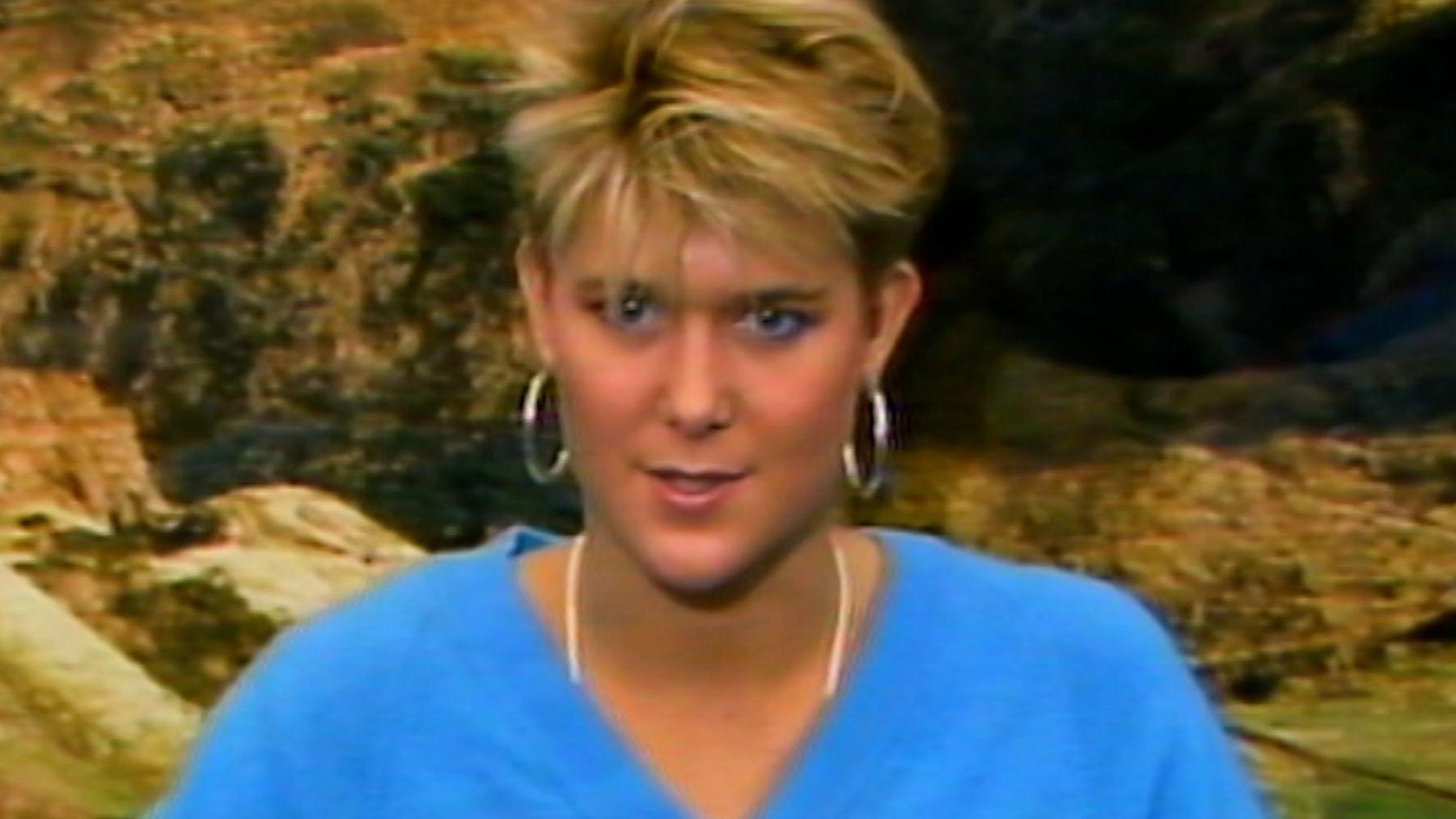 Annette Cowley in 1986. She has short hair and is wearing a blue top and hooped earrings.