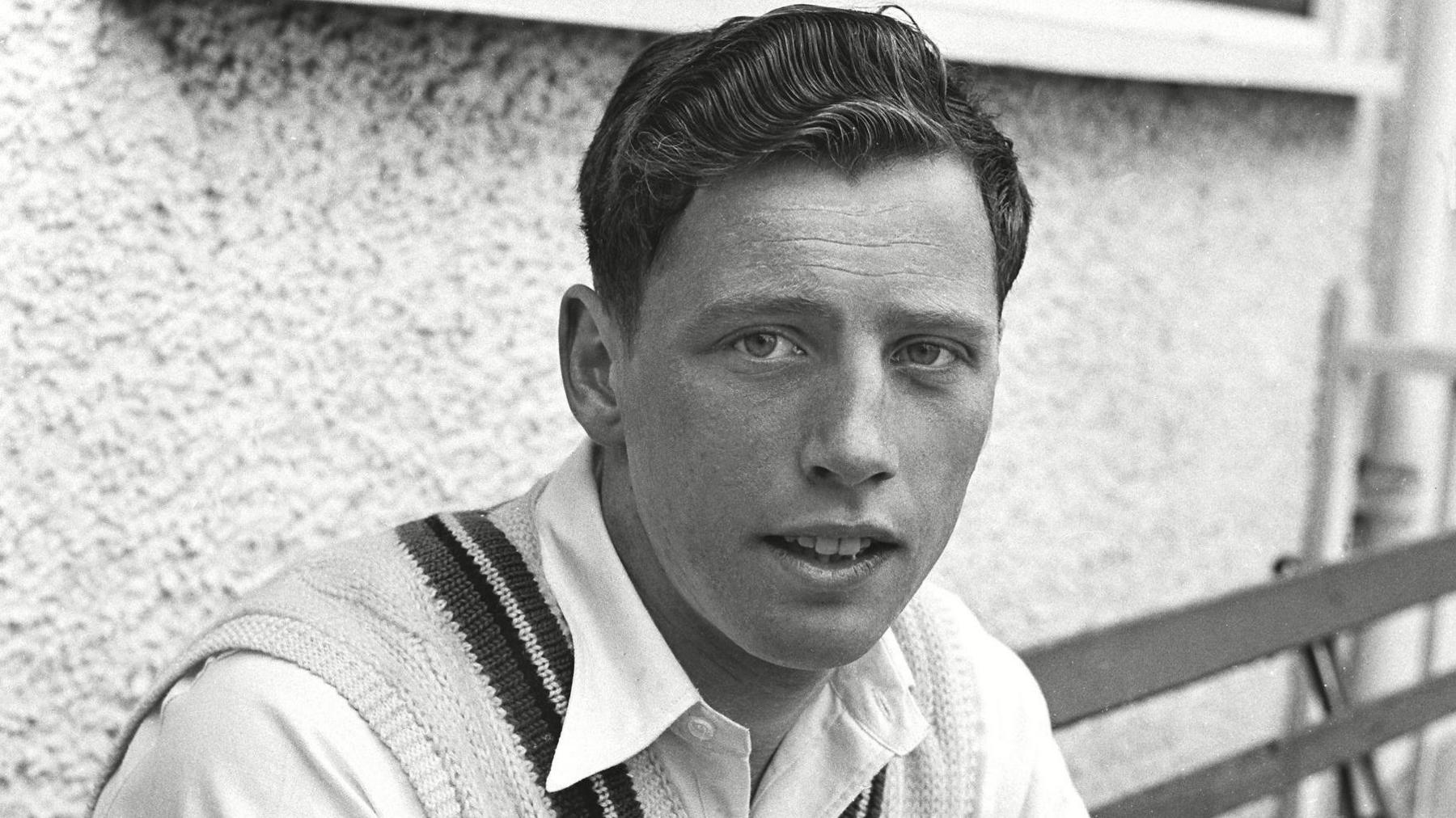 A black and white picture of Norman Gifford sitting outside the pavillion at New Road