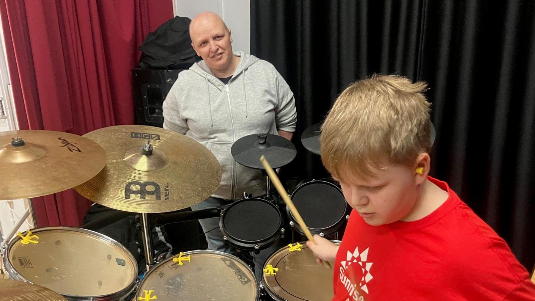 Jack drumming with his mum standing next to him