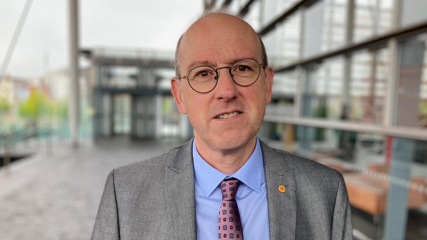 Llyr Gruffydd AS, cadeirydd y pwyllgor amgylchedd - yn sefyll o flaen y Senedd.