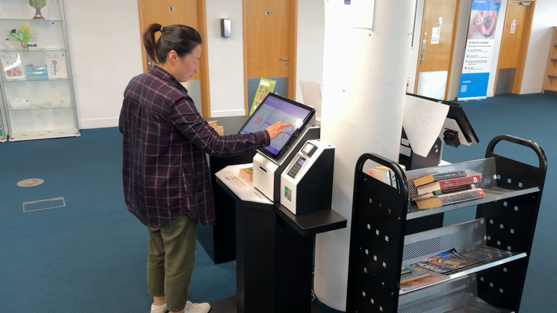 A female library staff member electronically scanning  books