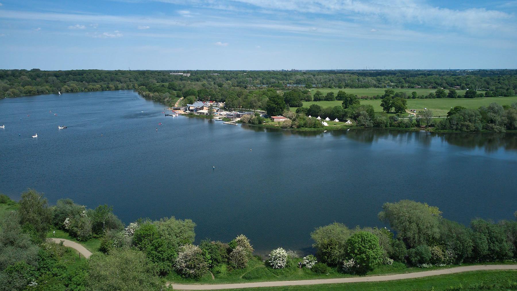 Aerial shot of a large lake surrounded by trees and fields