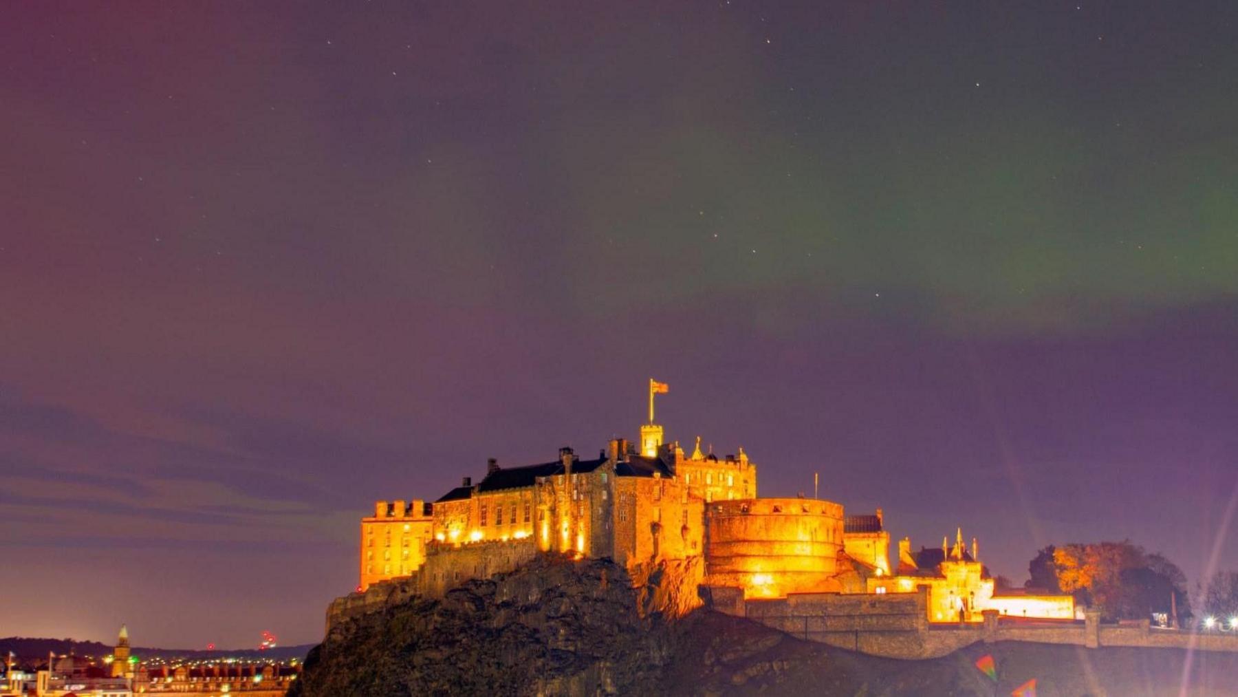 The purple and green sky above Edinburgh, the castle is lit up below.