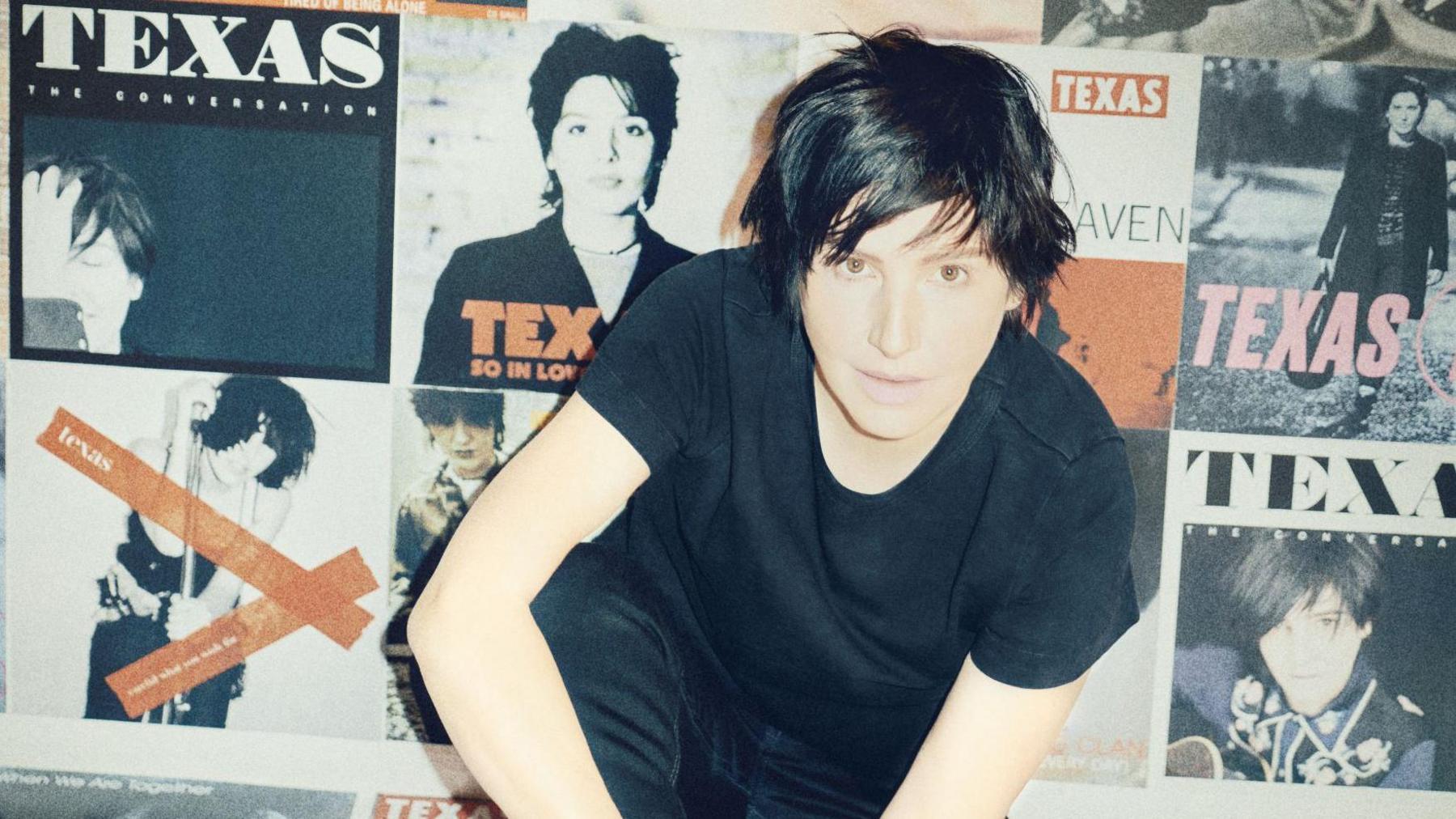 Sharleen is dressed all in black, including a black T-shirt. She is sitting on the floor surrounded by the covers of Texas' records.