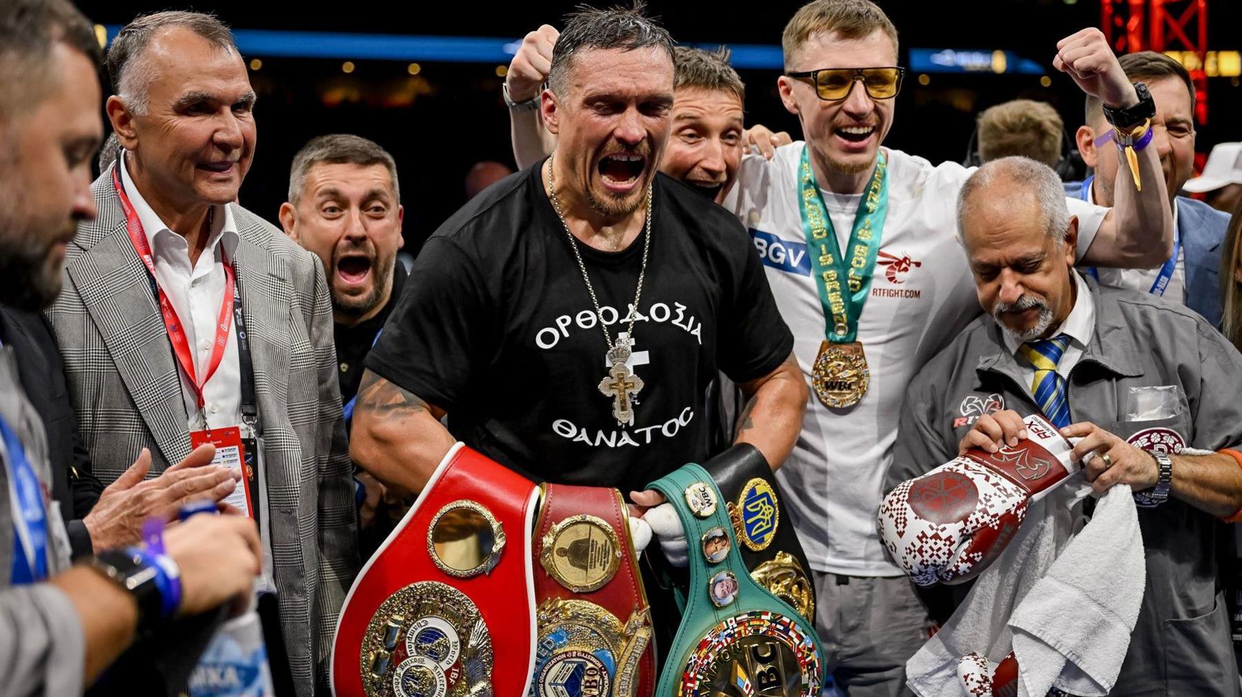Oleksandr Usyk holds the WBA, WBC, WBO and IBF heavyweight titles and is surrounded by his coaching team
