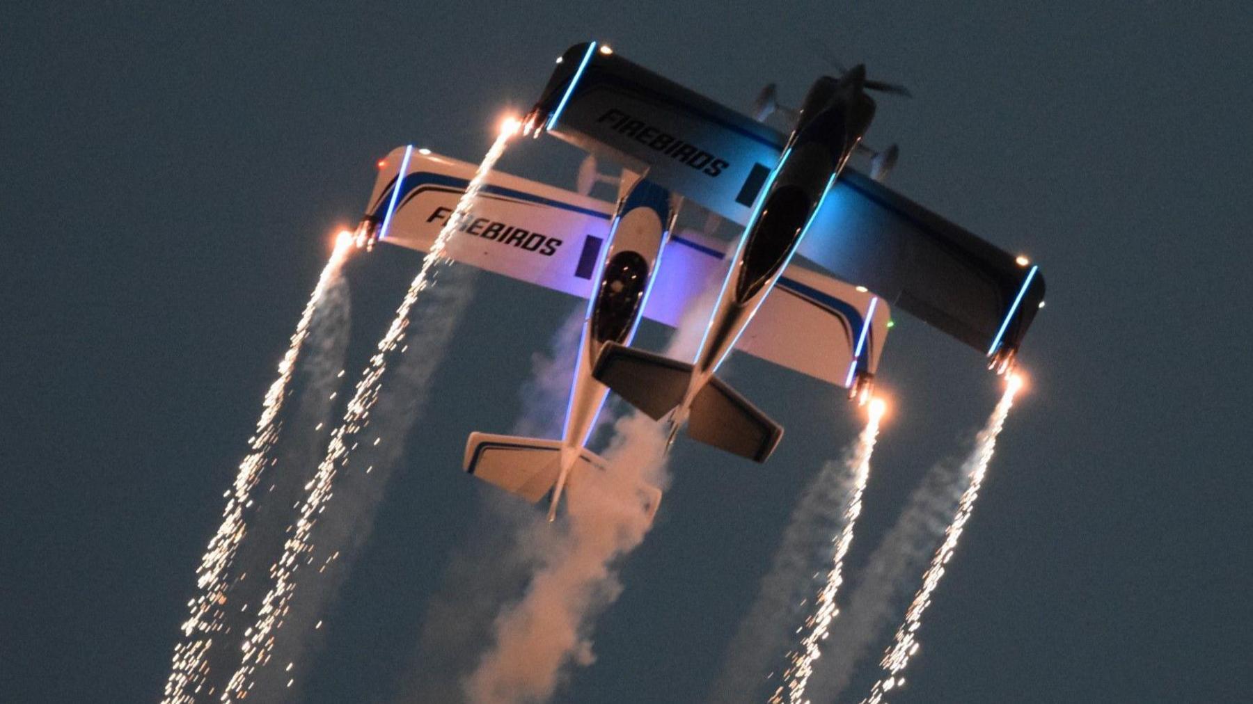 Two planes flying together with sparks coming off its wings