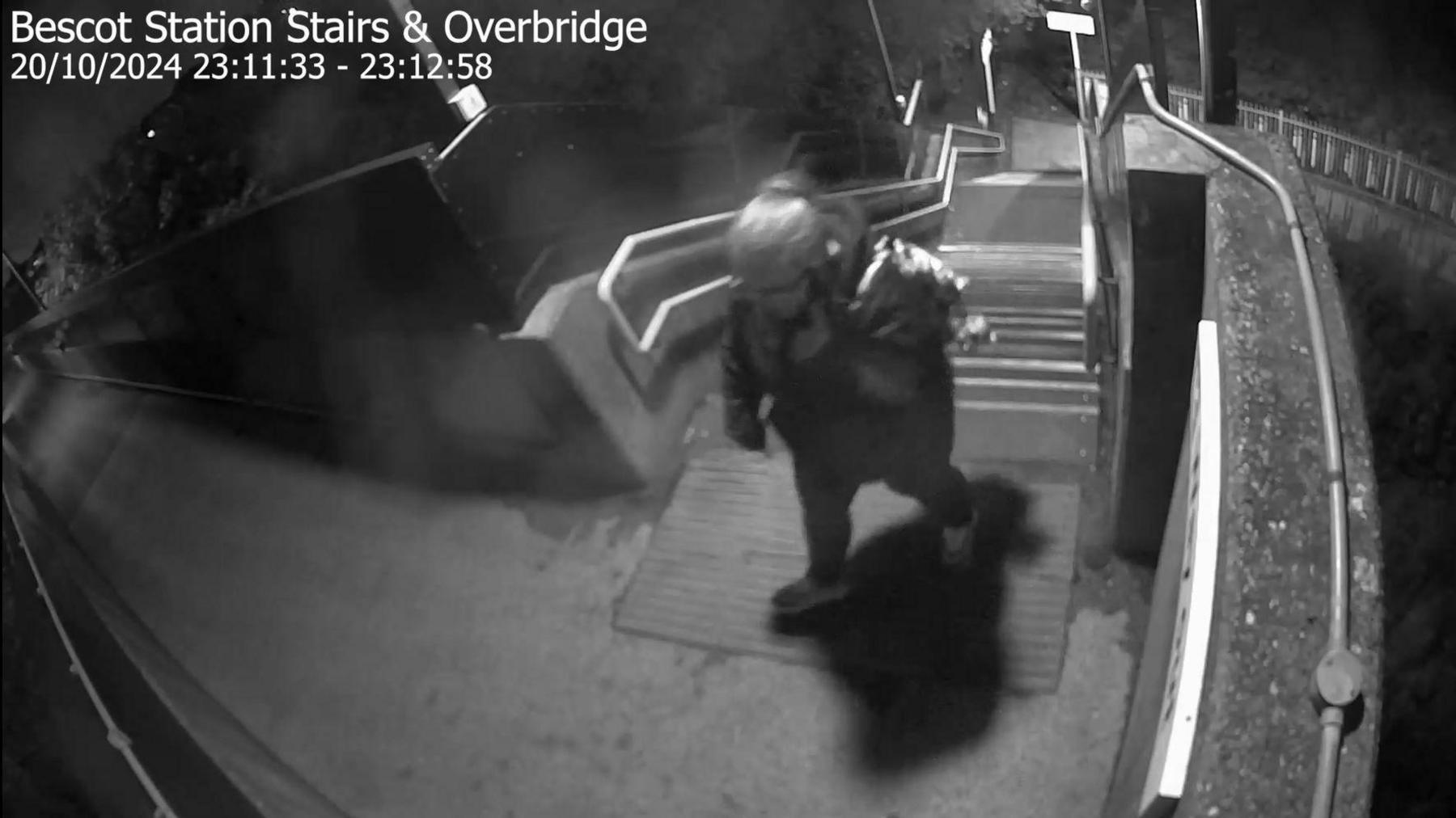 A black and white CCTV image shows Rhiannon Whyte walking up the stairs to the platform and talking on her phone.