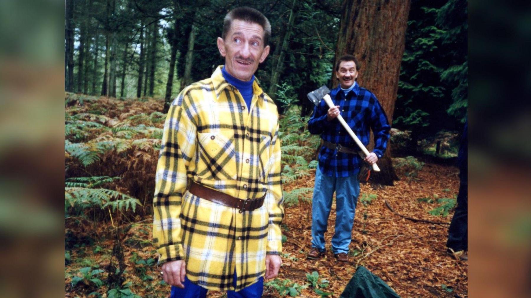 An images from the CBBC series ChuckleVision, showing Barry Chuckle in the foreground while his brother Paul brandishes and axe behind him.