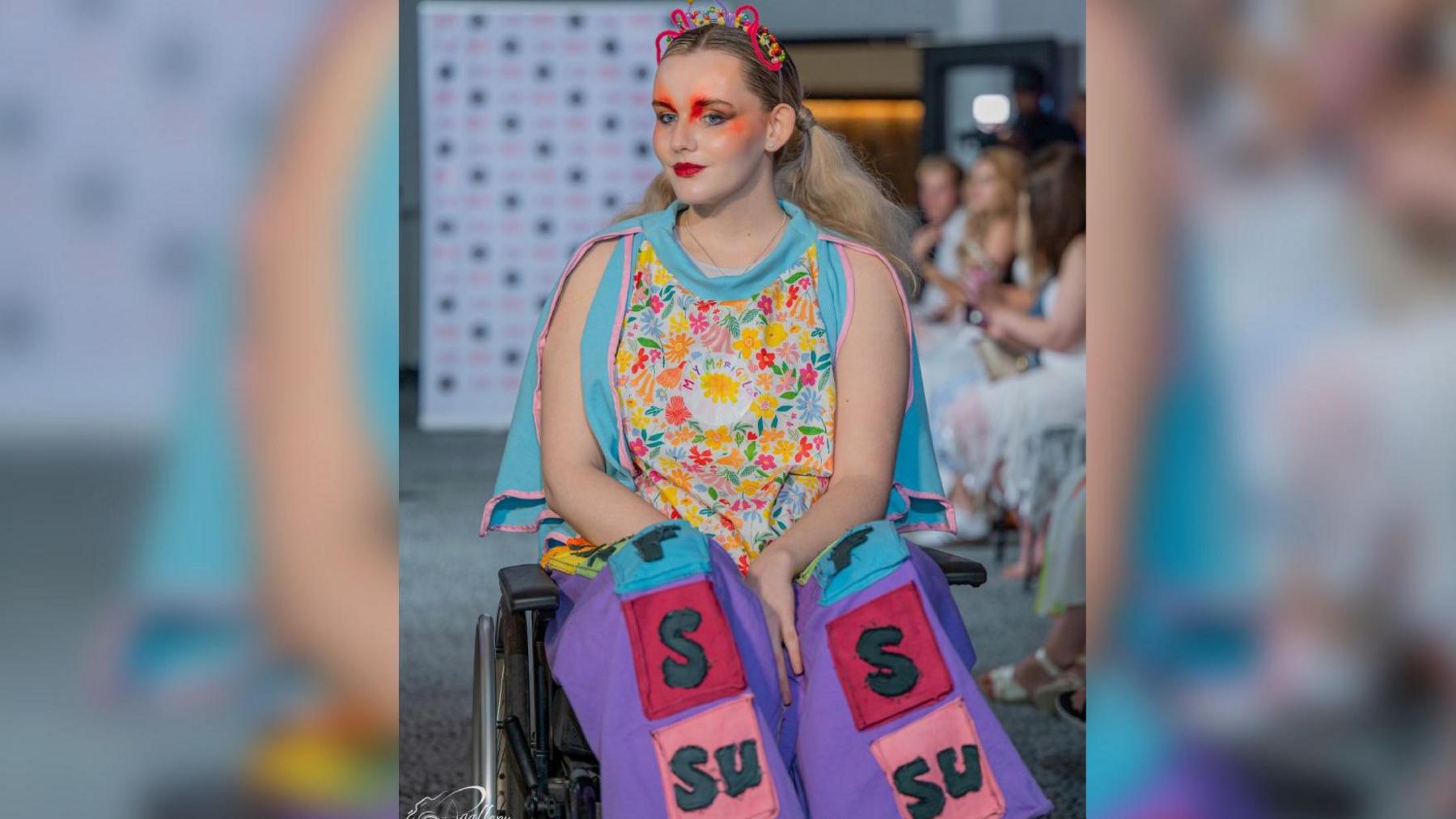 A model in a wheelchair wearing one of May's designs on a fashion show's catwalk.