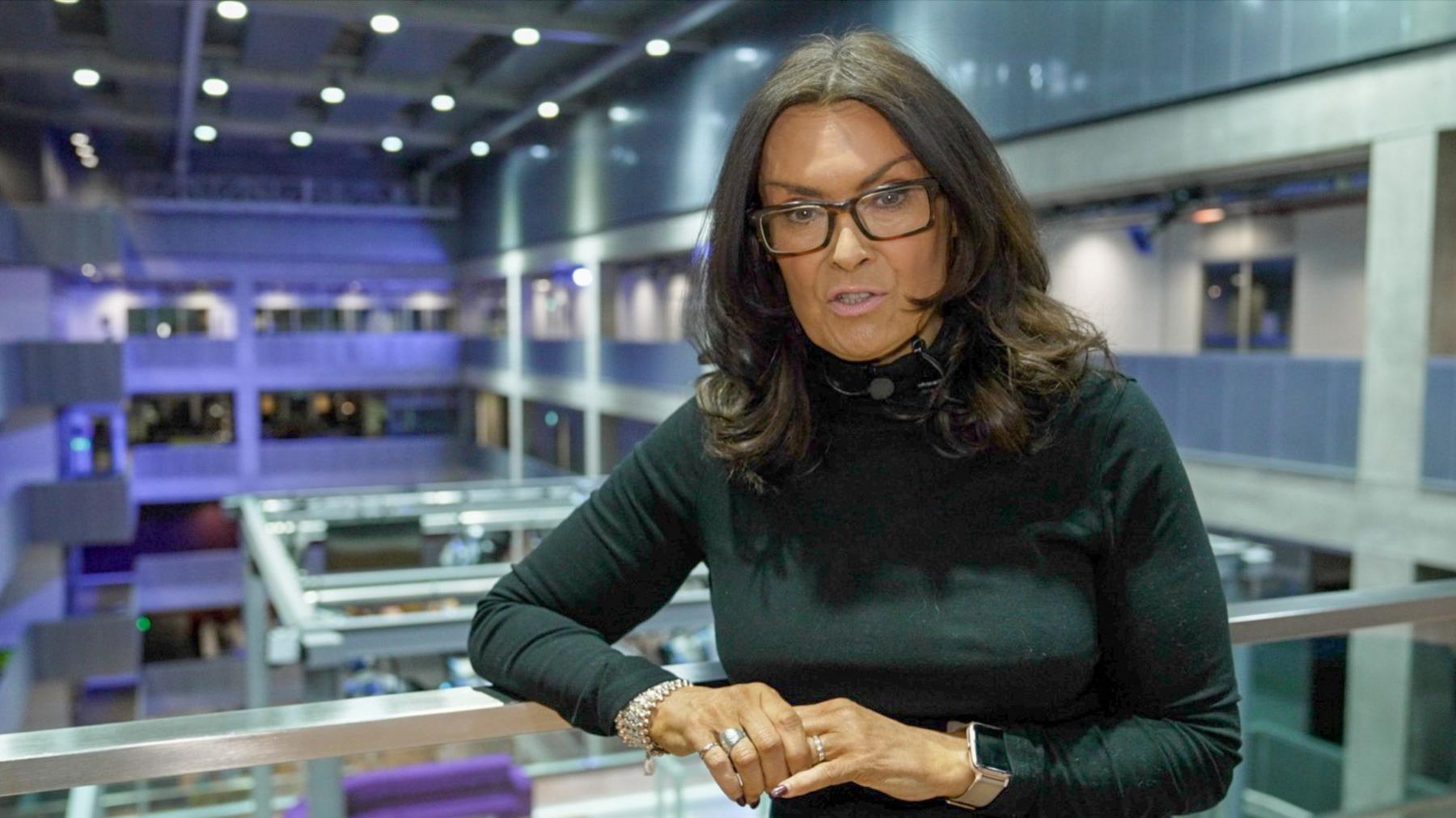 BBC weather presenter Judith Ralston stands in the atrium of BBC Scotland's Pacific Quay headquarters in Glasgow, wearing a black dress.