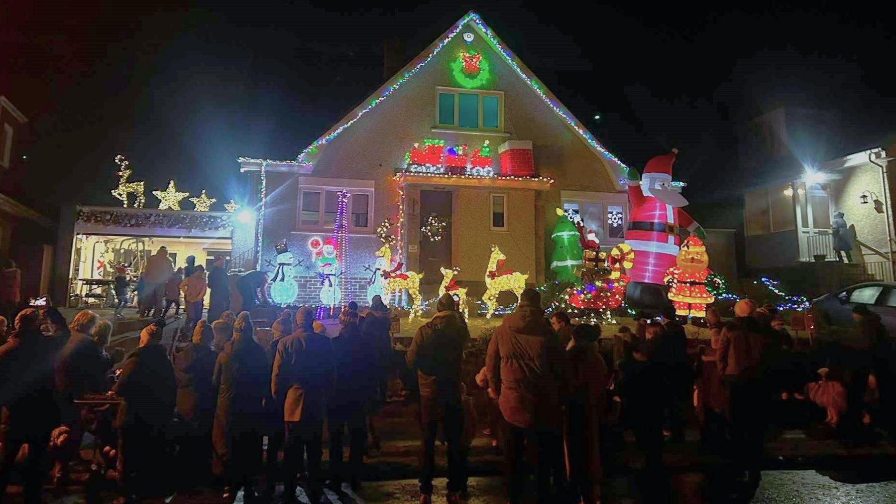 People looking at the christmas light display house