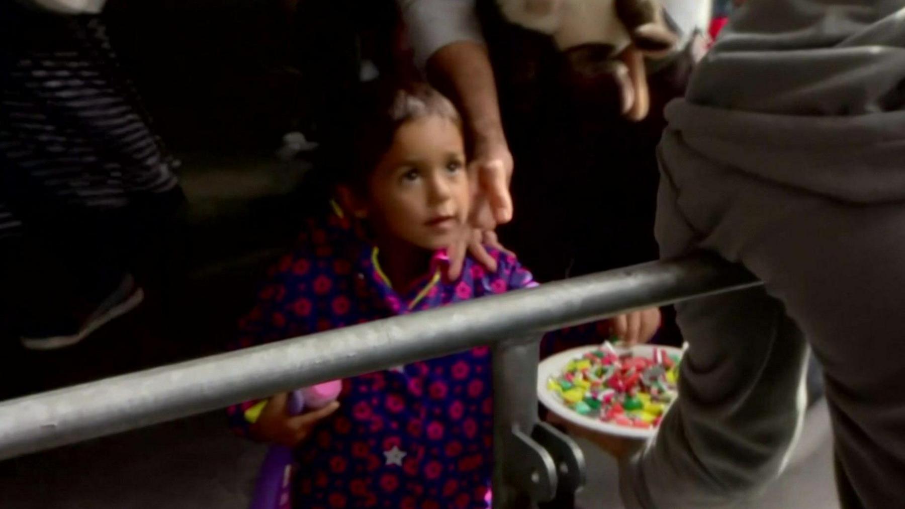 A little girl is offered a plateful of sweets as she arrives in Germany