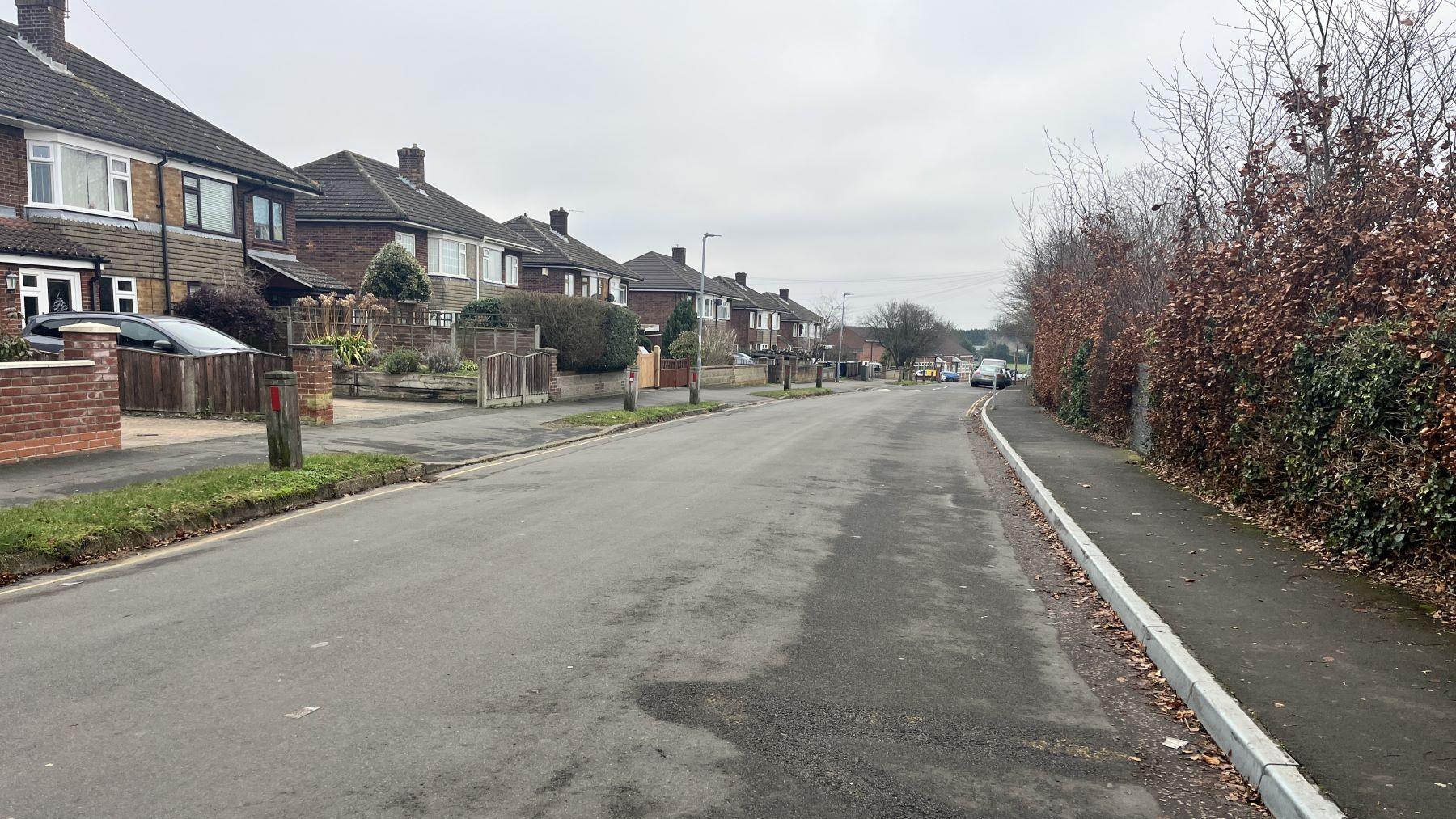 Upper Breckland Road. Semi-detached houses line one side of the road while hedges line the other