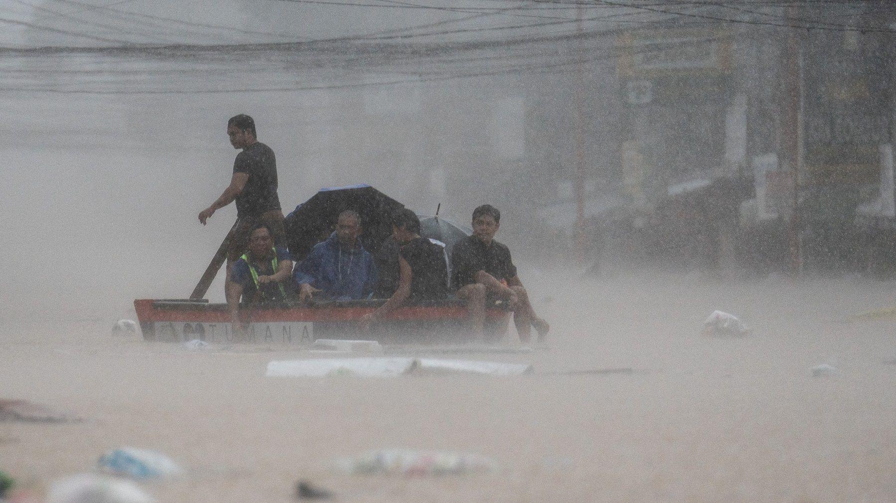 Rescuers assist residents on a boat along a flooded road following heavy rains brought by Typhoon Gaemi, in Marikina City, Metro Manila