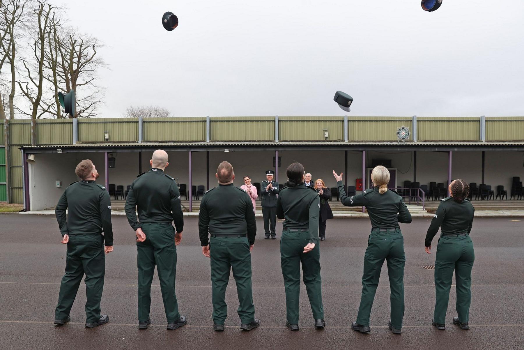 Police officers throwing hats in the air at passing out parade