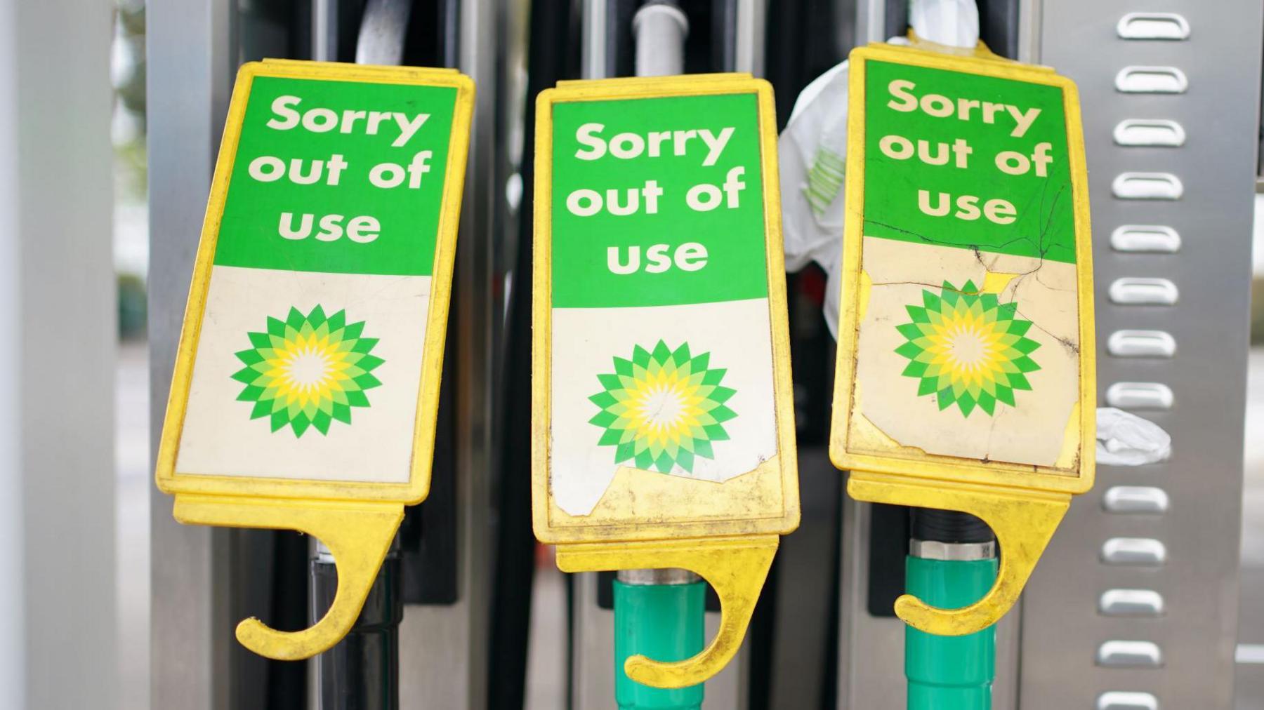 Three BP petrol pumps with yellow, white and green tags on them that read: "Sorry out of use".