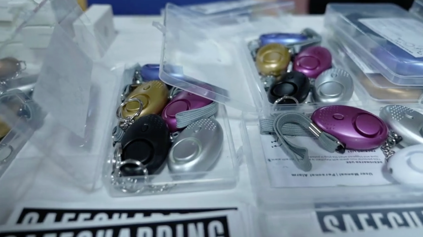 rows of different coloured rape alarms in plastic boxes on a table