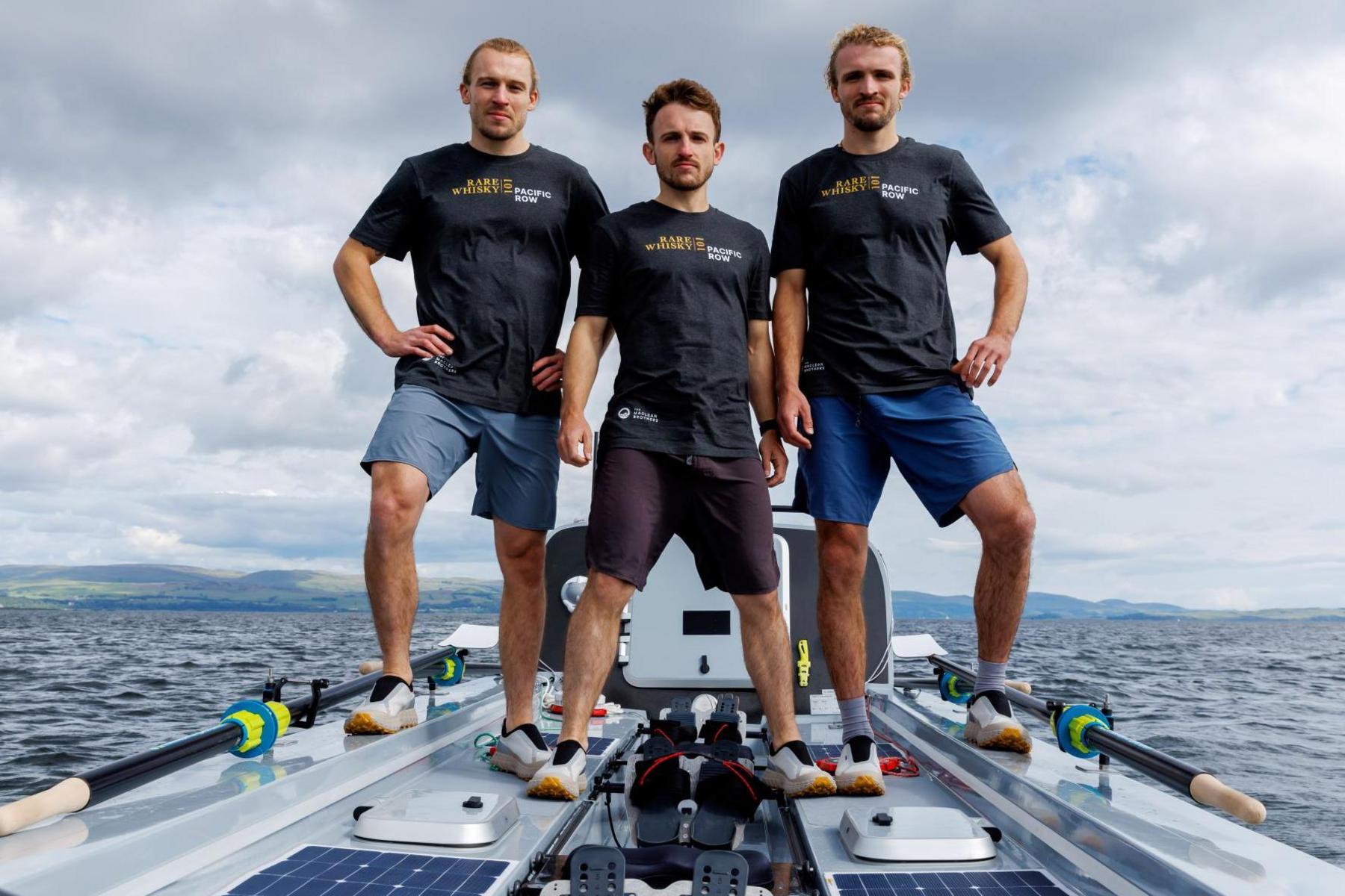 Jamie, Ewan and Lachlan Maclean are dressed in dark blue T-shirts and shorts and are standing on their boat.