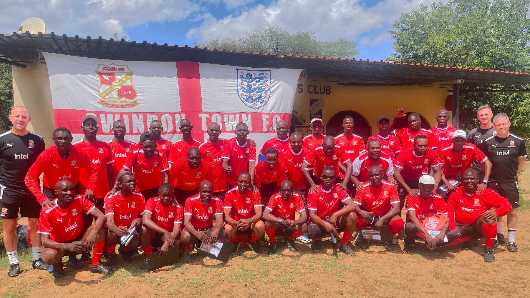 Image of people in Africa stood in bright red Swindon Town kits