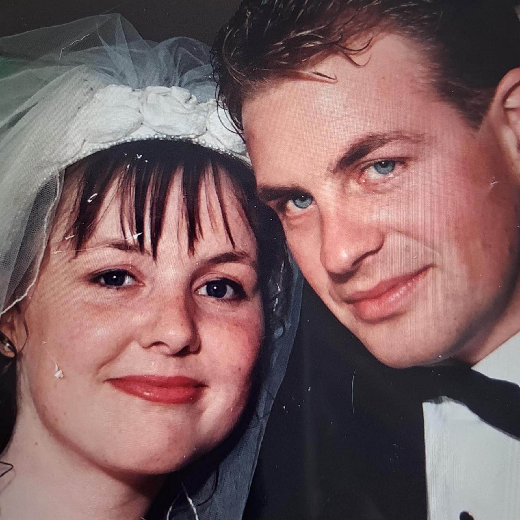 The couple are pictured at their wedding. Murdina is wearing her wedding dress. Archie is wearing a black jacket, bow tie and a white shirt. They are smiling into the camera.