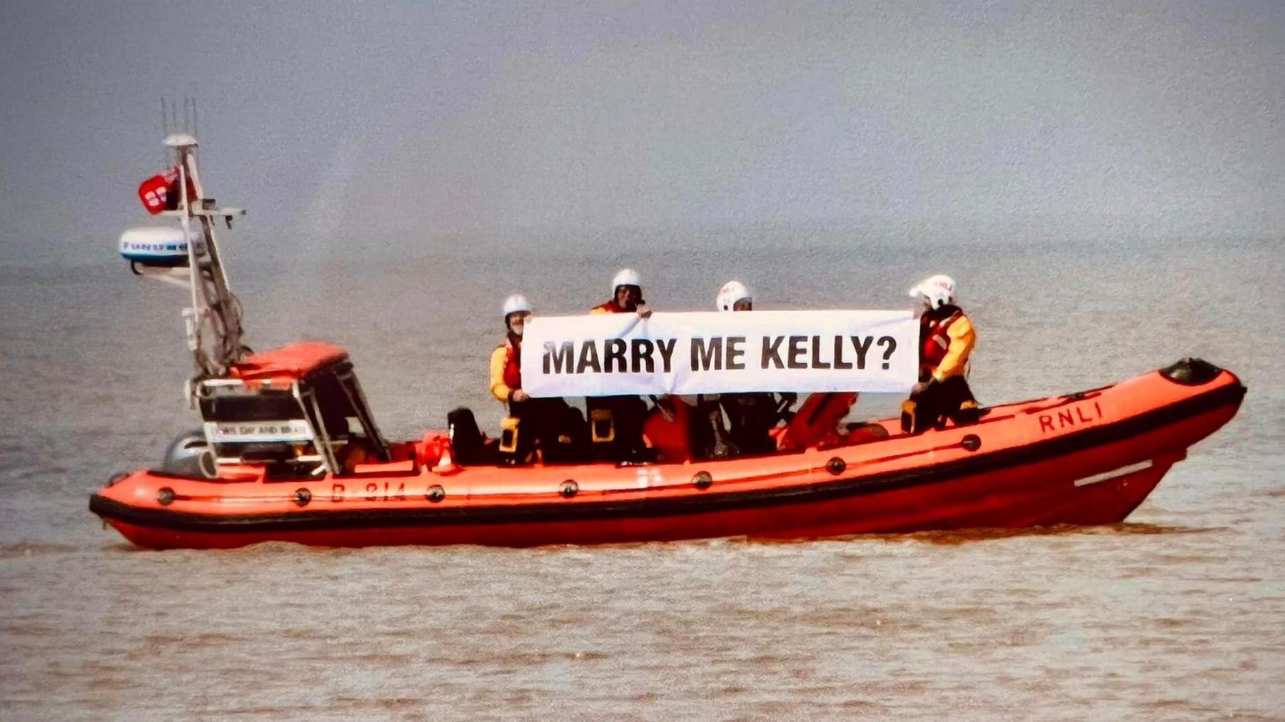 Crew members holding up sign saying 'Marry me?'