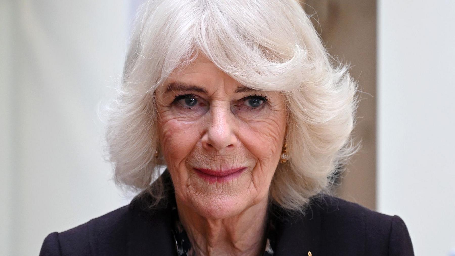 Queen Camilla looks away from camera while wearing a black suit jacket, pictured in London in February.
