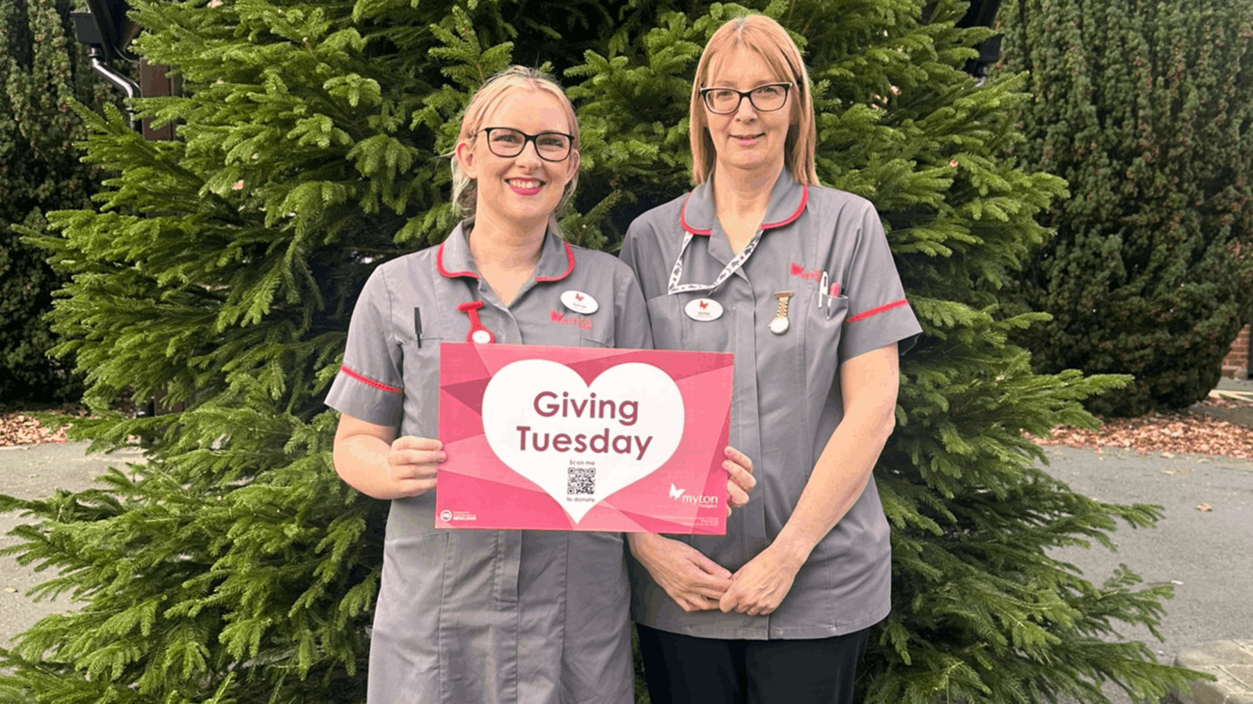 Two nurses holding a card that says giving Tuesday on it