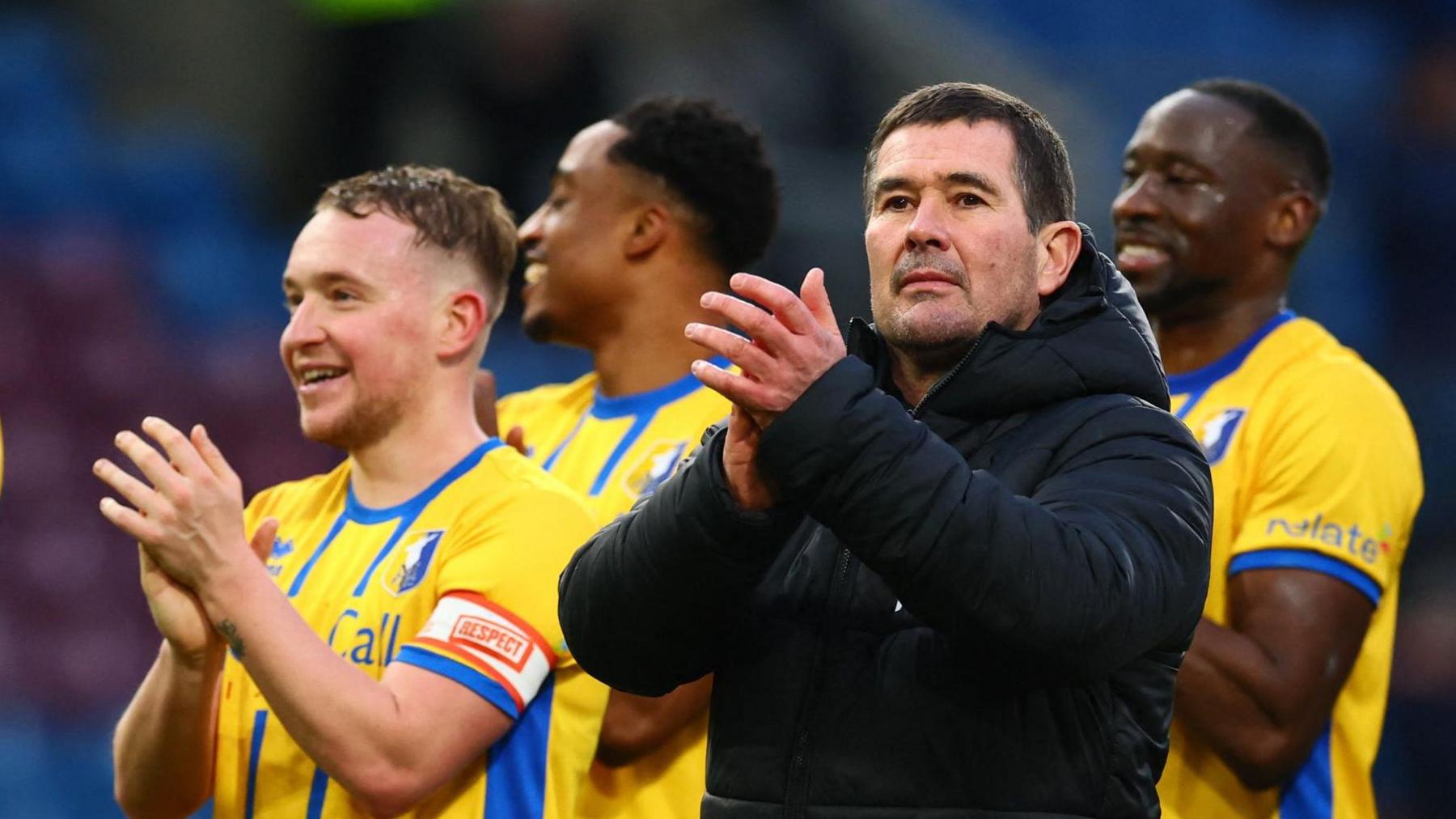 Manager Nigel Clough stands with his players and claps his hand in appreciation after Mansfield beat Burnley in the FA Cup