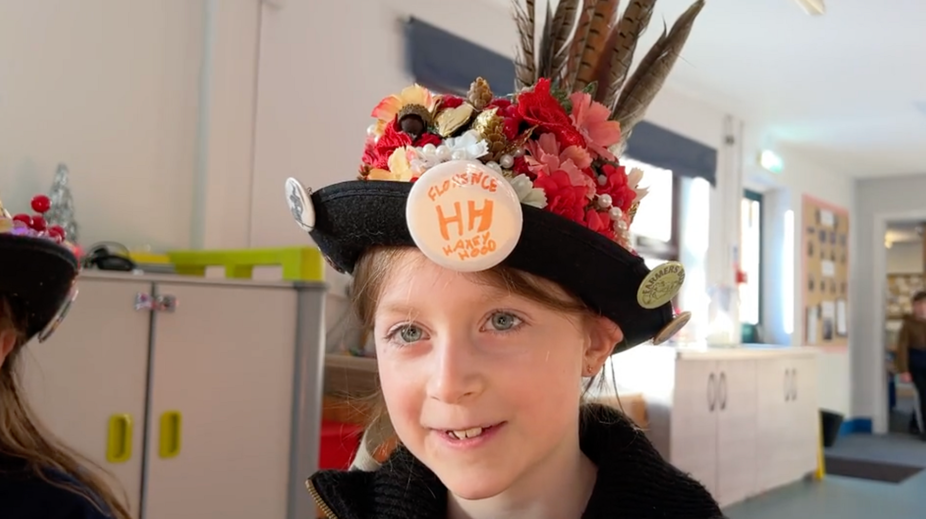 a young girl wearing a hat with lots of flowers and feathers.