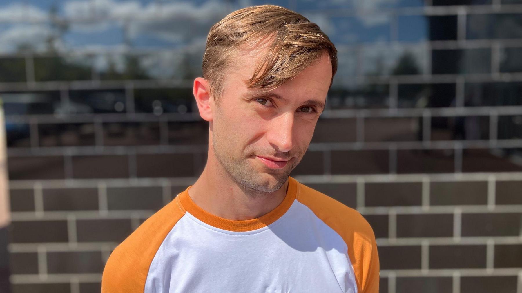 Man with orange and white t shirt outside Stadium MK