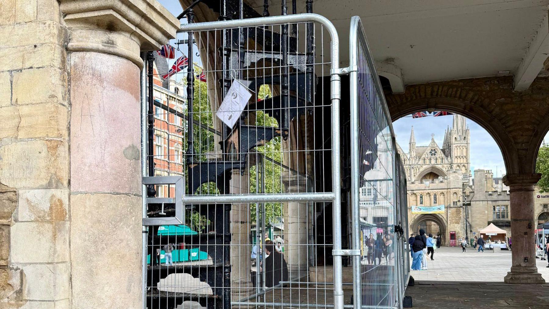A metal fencing around a black staircase with the cathedral in the background.