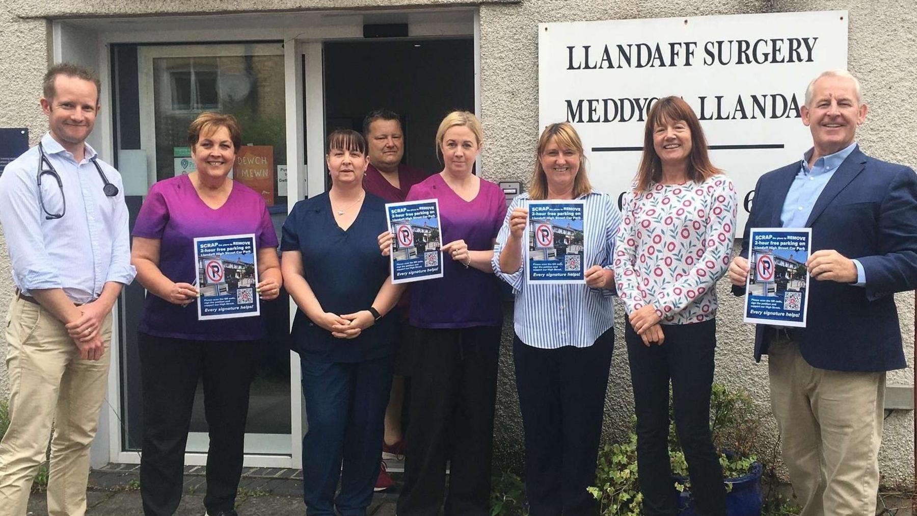 Llandaff councillor Sean O'Driscoll stood with seven members of Llandaff doctors surgery, four of which holding up campaign signs opposing the parking proposal. They are stood in front of the surgery, with a large white sign behind them saying 'Llandaff surgery' in both English and Welsh. 