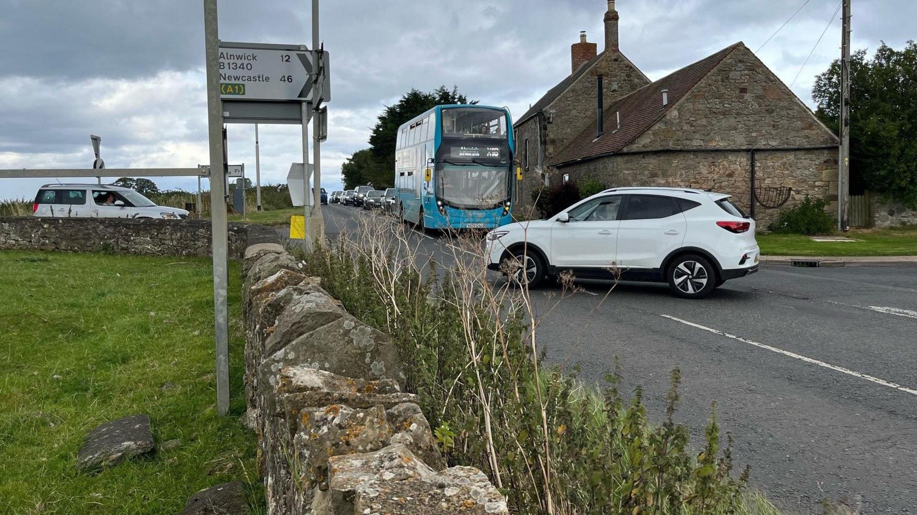 A white car pulling out at a junction while a bus approaches.