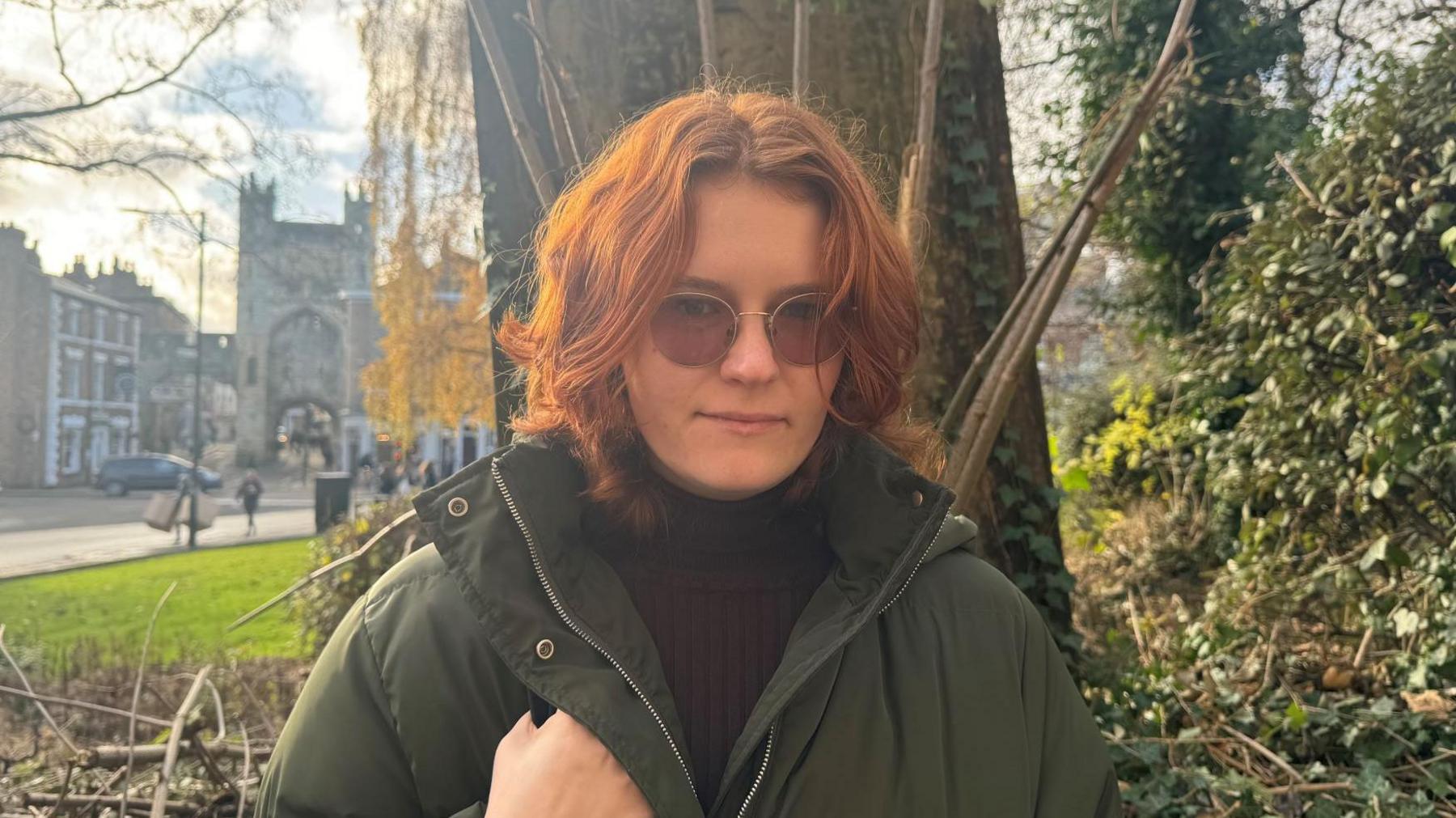 Caitlin, who is wearing a winter coat and sunglasses, stands outside the Jobcentre in York.