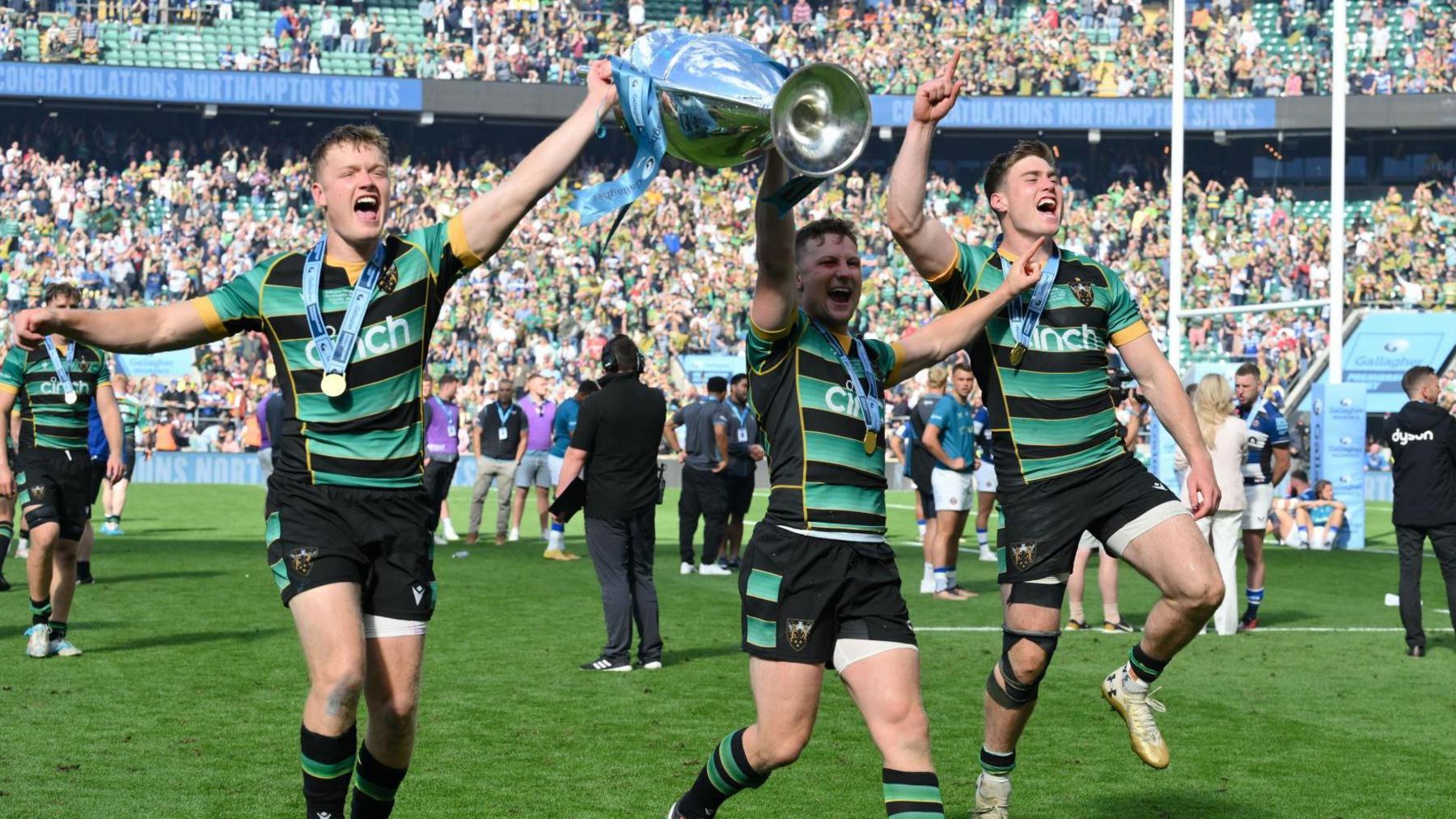 Northampton players hold the Premiership trophy in celebration on the pitch at Twickenham