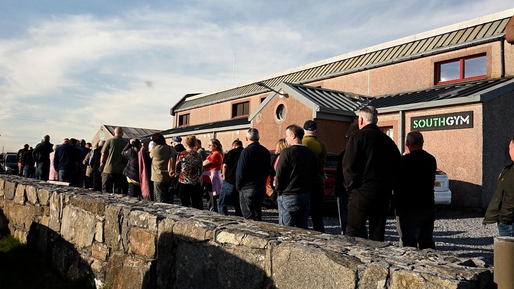 Daoine a' feitheamh taobh a-muigh Talla a' Chinn a Deas