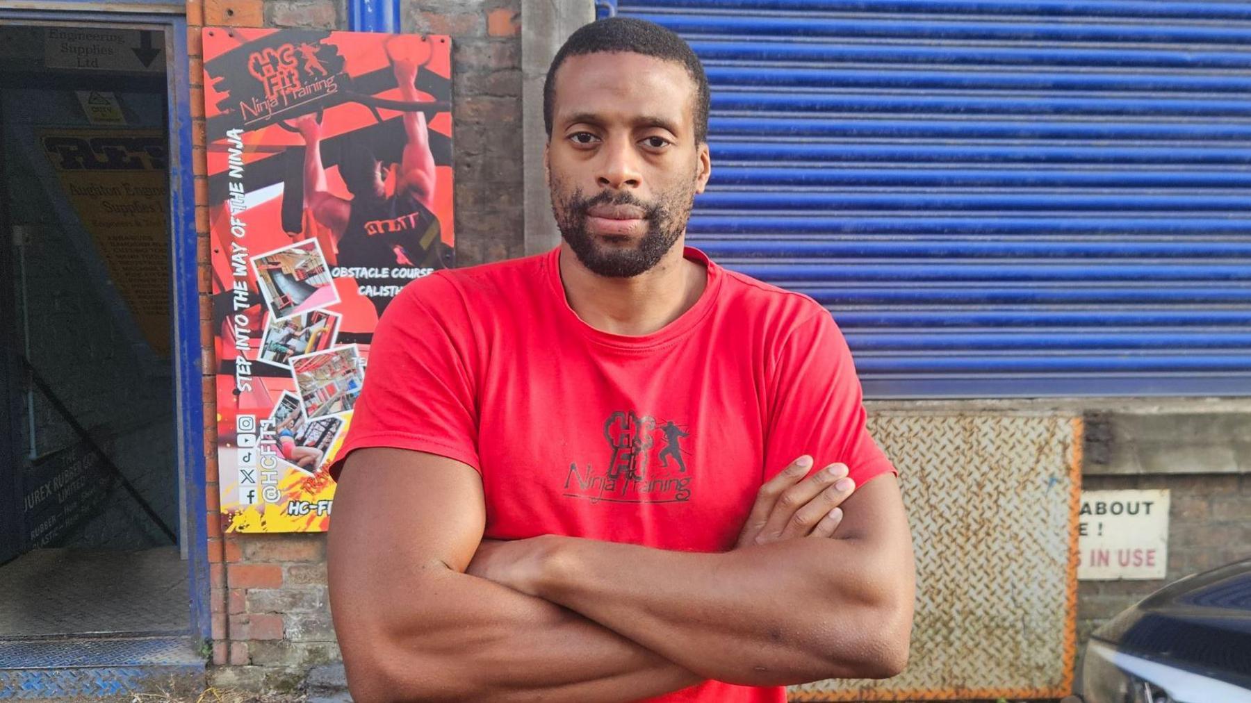 Henry Cookey has short black hair and a black beard and is stood outside HC Fit Ninja Training gym