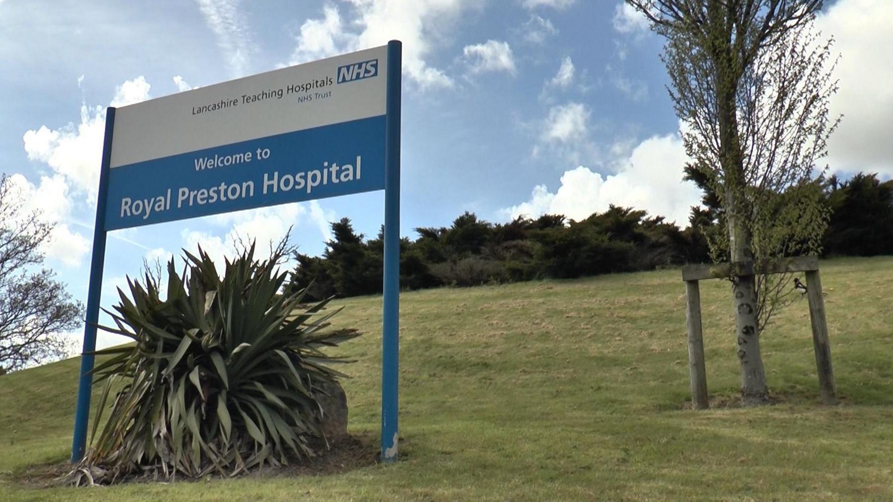 A white sign mounted on a grassy hill reads: Welcome to Royal Preston Hospital.