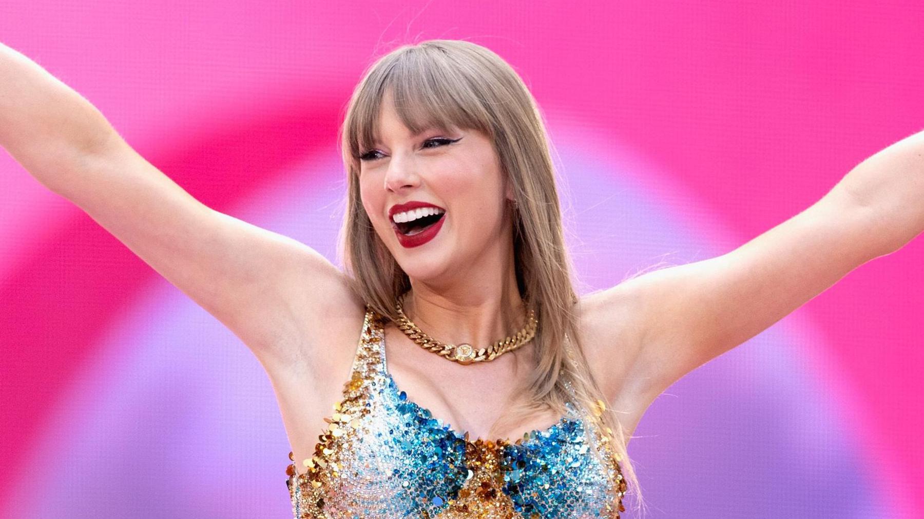 Taylor Swift performs on stage in Wembley Stadium, London wearing a blue and gold embellished bodysuit